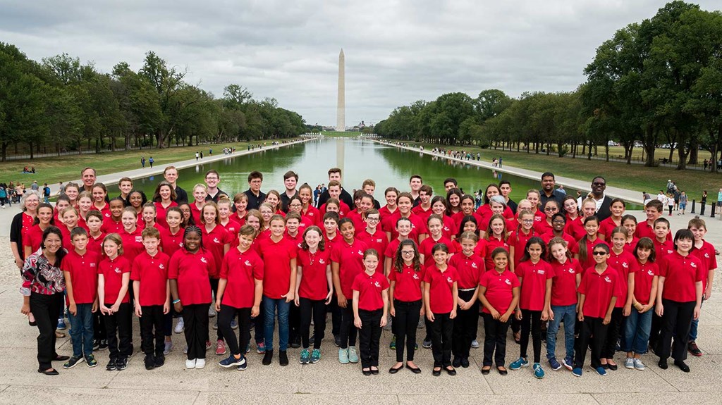 Childen's Chorus of Washinton in front of the Washington Monument in red shirts