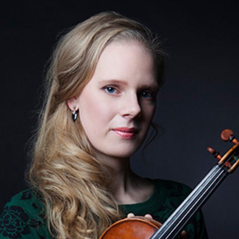 Violinist Simone Lamsma in a green and black dress and holding her instrument. Photo  by Juan Carlos Villarroel
