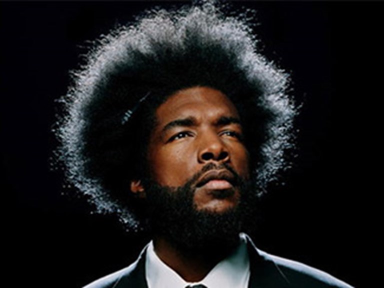 Chin lifted Questlove is backlit, highlighing his uneven afro eges