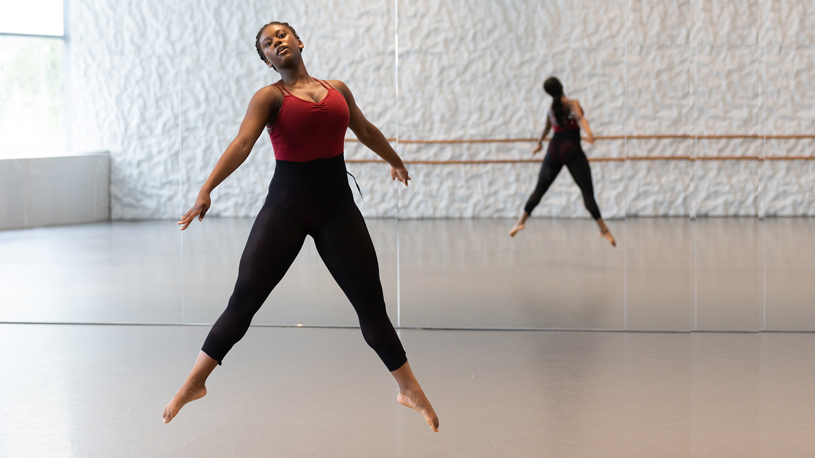 A Dance Lab participant in black tights with a red leotard top is dancing in a Kennedy Center studio
