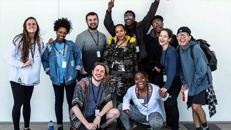 Ten college students pose for a happy group photo outside.