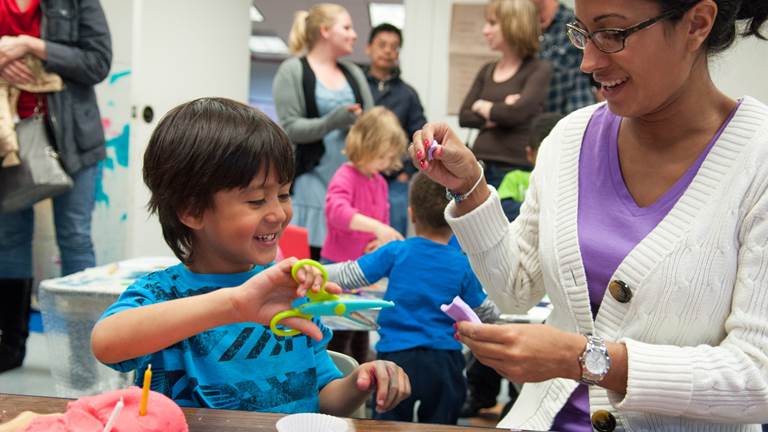A child and an adult volunteer work on a project in a classroom together