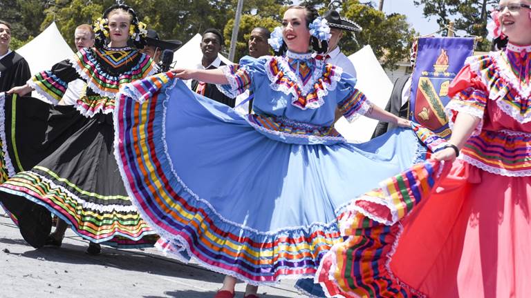 Three women dancing in colorful dresses