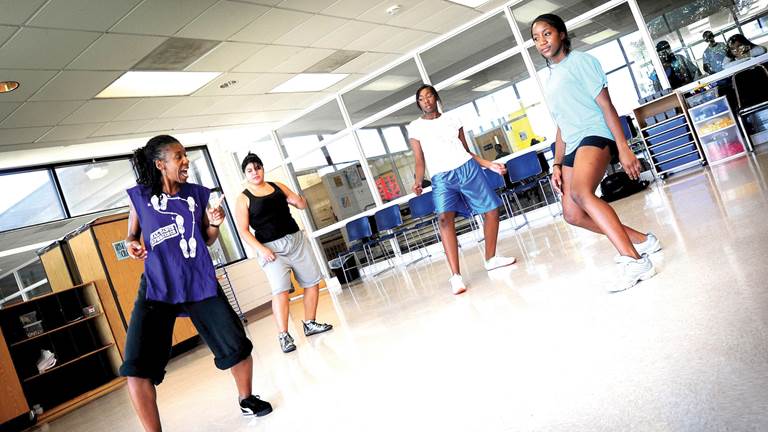 A dance teacher instructs her students in an open studio