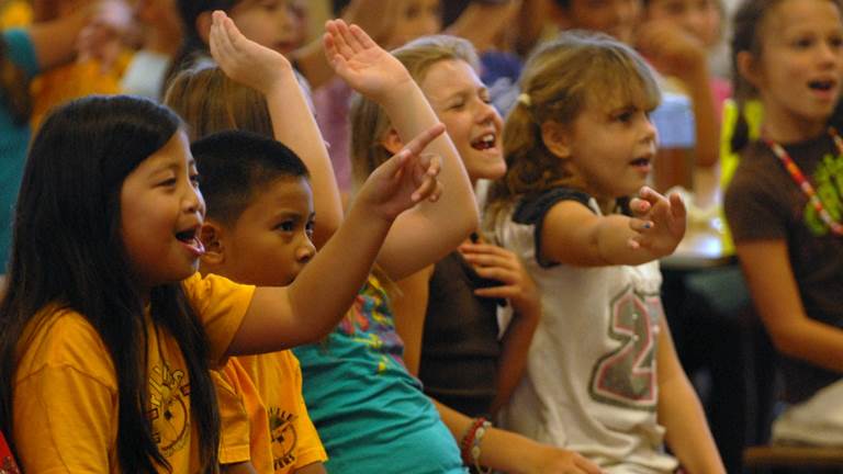 A group of elementary school students enjoy a performance