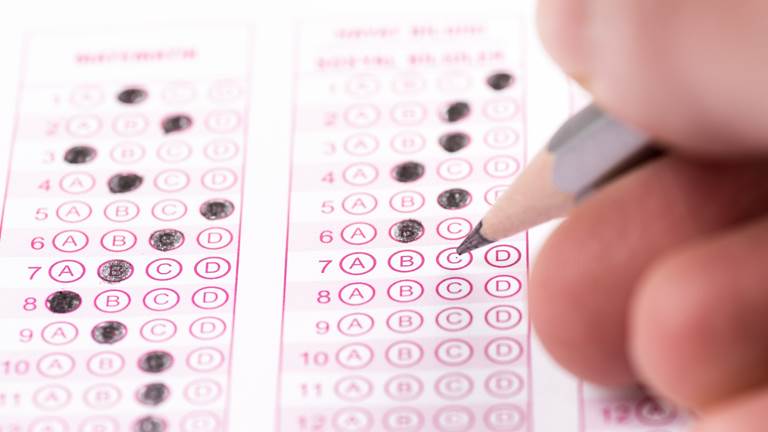 A hand bubbles in answers on a multiple choice test