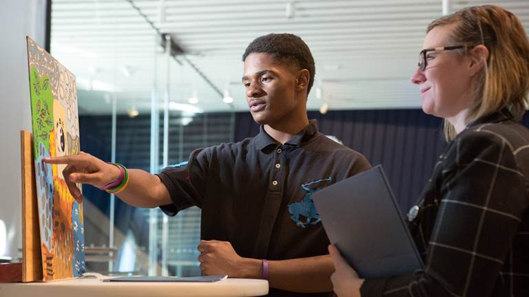 A students talks to his teacher about a painting.