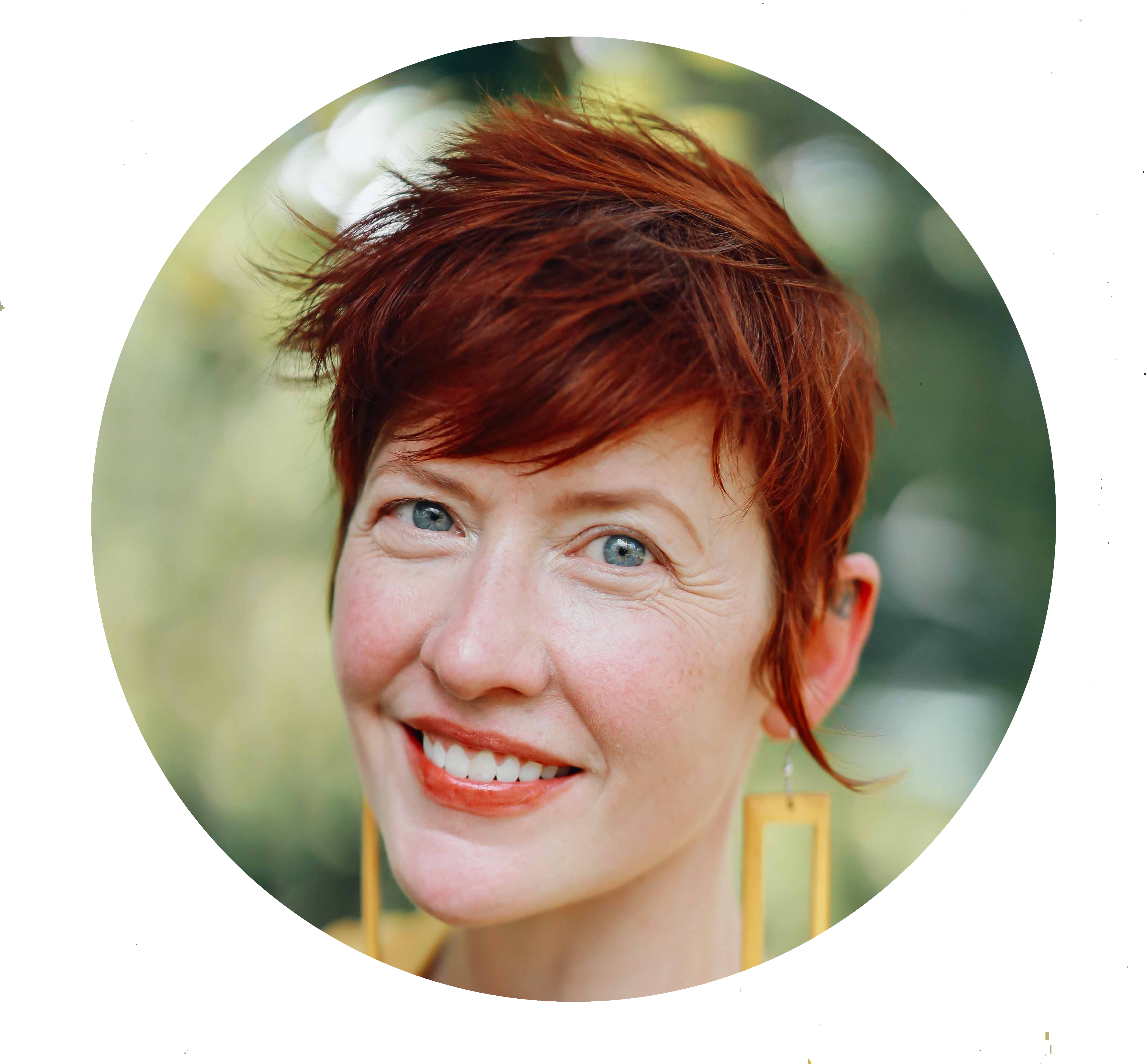 Larua Lee Gulledge , a white woman with short red hair wearing a yelllow dress and large rectangular earrings, is smiling.