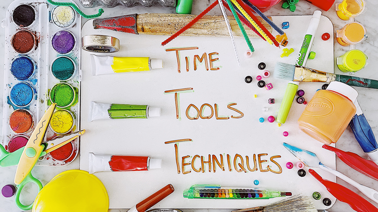 A dry-erase board with the word, time, tools, and  techniques written.  Colorful art supplies are framing the board.