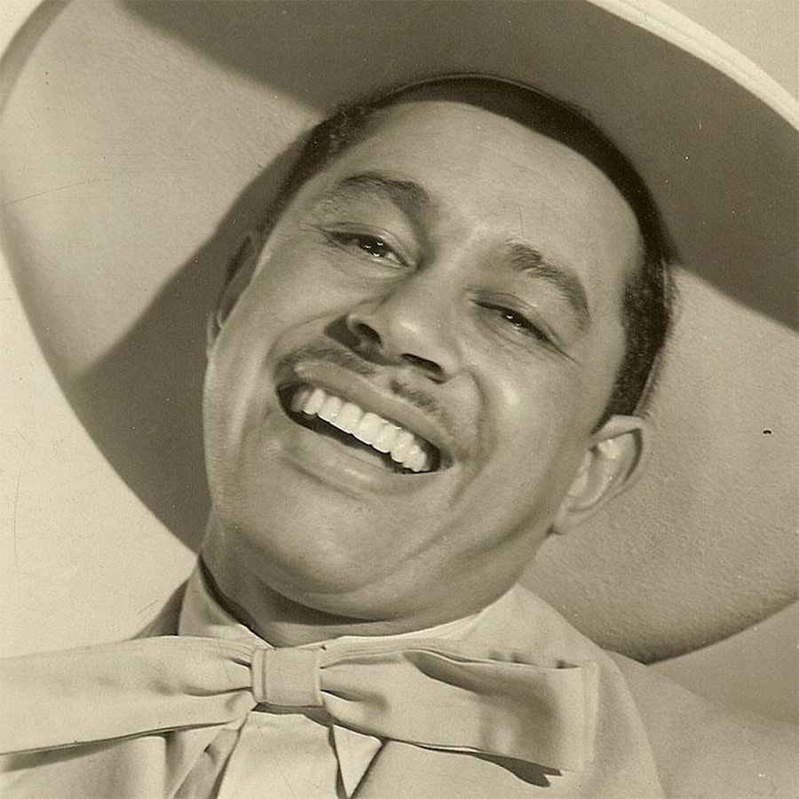 A black-and-white photo of jazz vocalist and bandleader Cab Calloway. Cab is smiling while wearing a wide-brimmed hat.