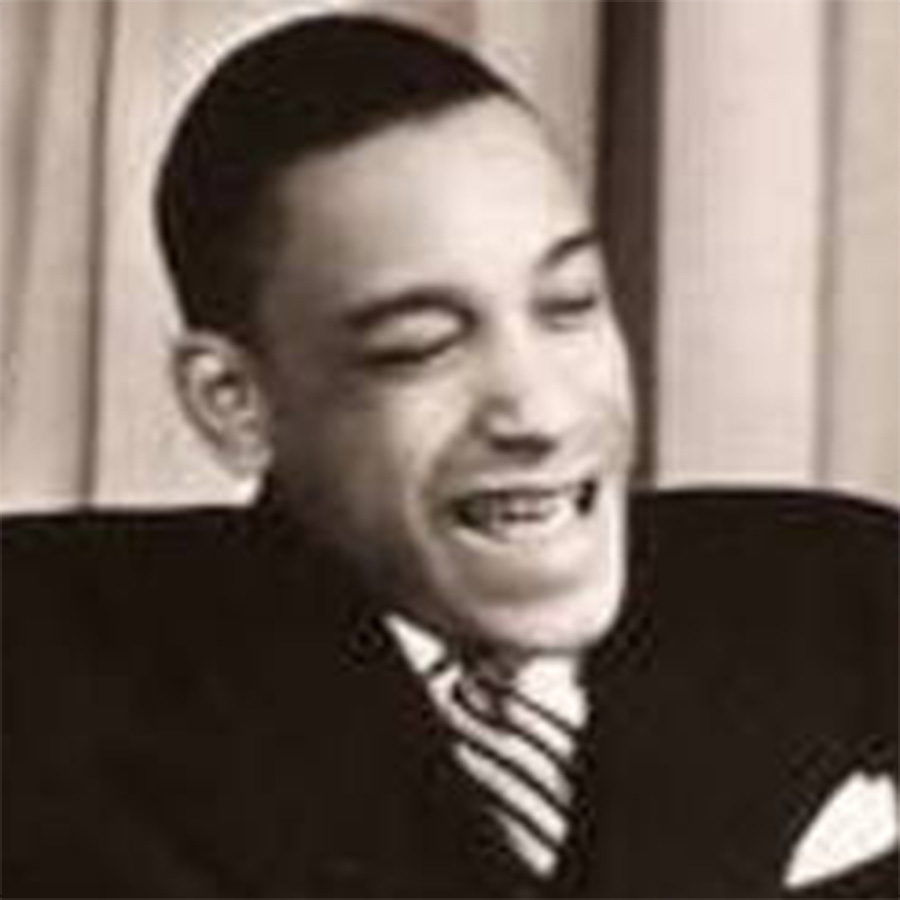 A black-and-white photo of jazz drummer and bandleader Chick Webb. He wears a dark suit with a light dress shirt and striped tie.
