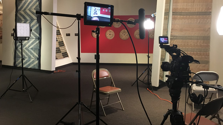 A production set up with a camera and lights in an empty room