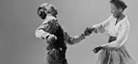 A black-and-white cropped photo of two dancers moving together.