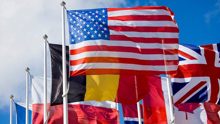 Flag poles with the American flag and many other international flags behind it.