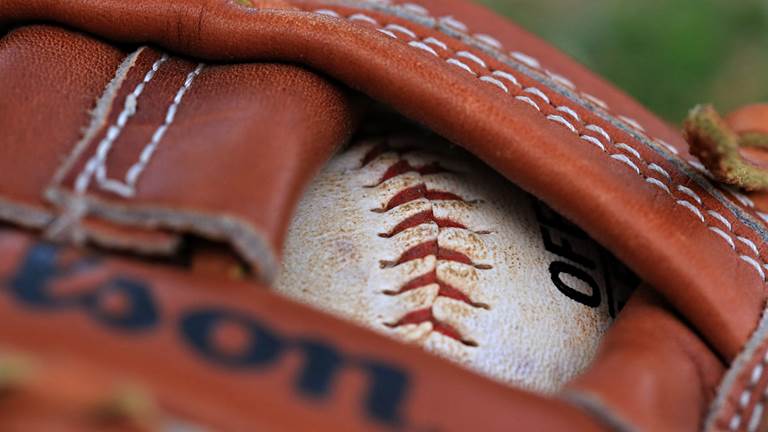 A baseball glove holding a baseball.