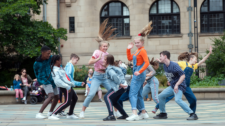 A group of teenagers dancing together outside.