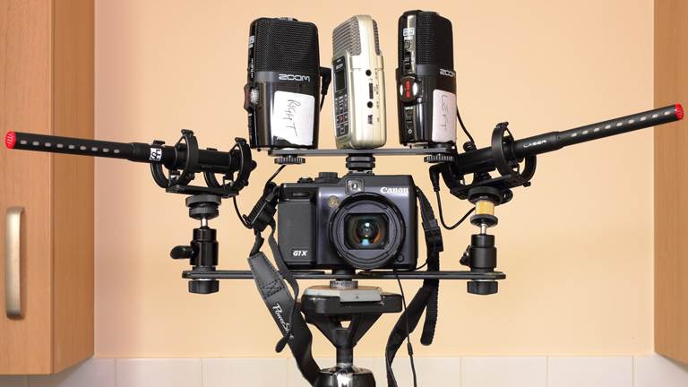 A video camera set-up with three microphones anchored on top.