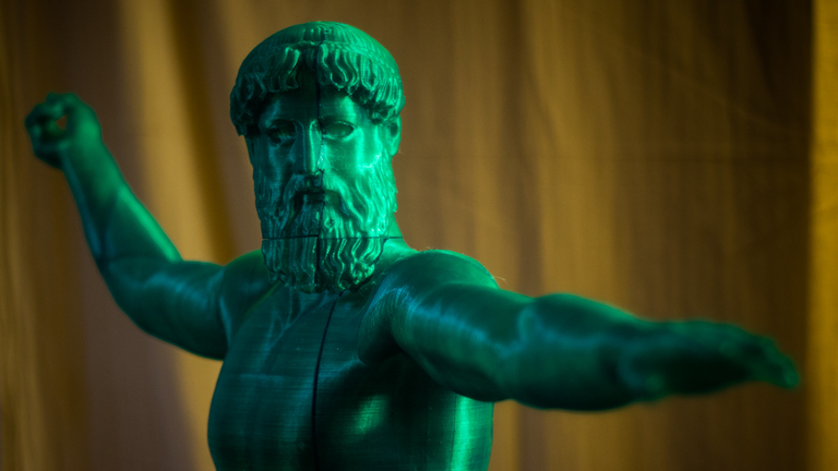A green statue of a Greek God.