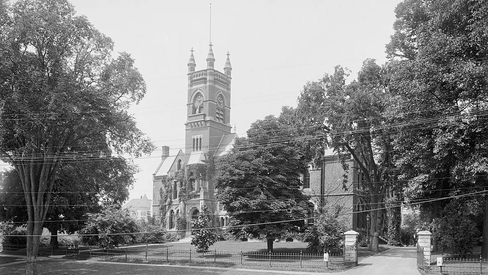 A vintage photo of a college building partially obstructed by trees and powerlines.jpg