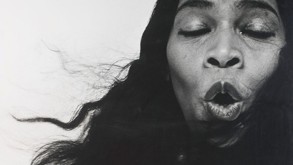 A black and white closeup headshot of Marian Anderson. Her eyes are closed and her mouth is open in an &ldquo;O&rdquo; shape as though she is in the middle of singing a note. Some of her hair is being blown across her face.