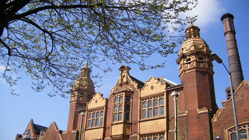 An exterior photograph of a brick academic building from its upper floor to the blue sky above it.