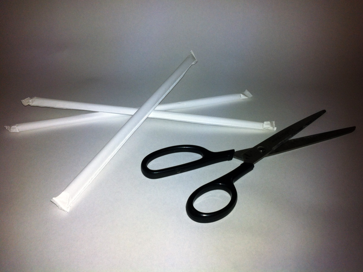 A photo of three wrapped drinking straws and a pair of scissors.
