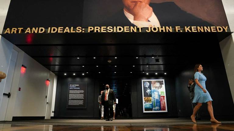 Image of visitors walking underneath Art and Ideals exhibit entryway