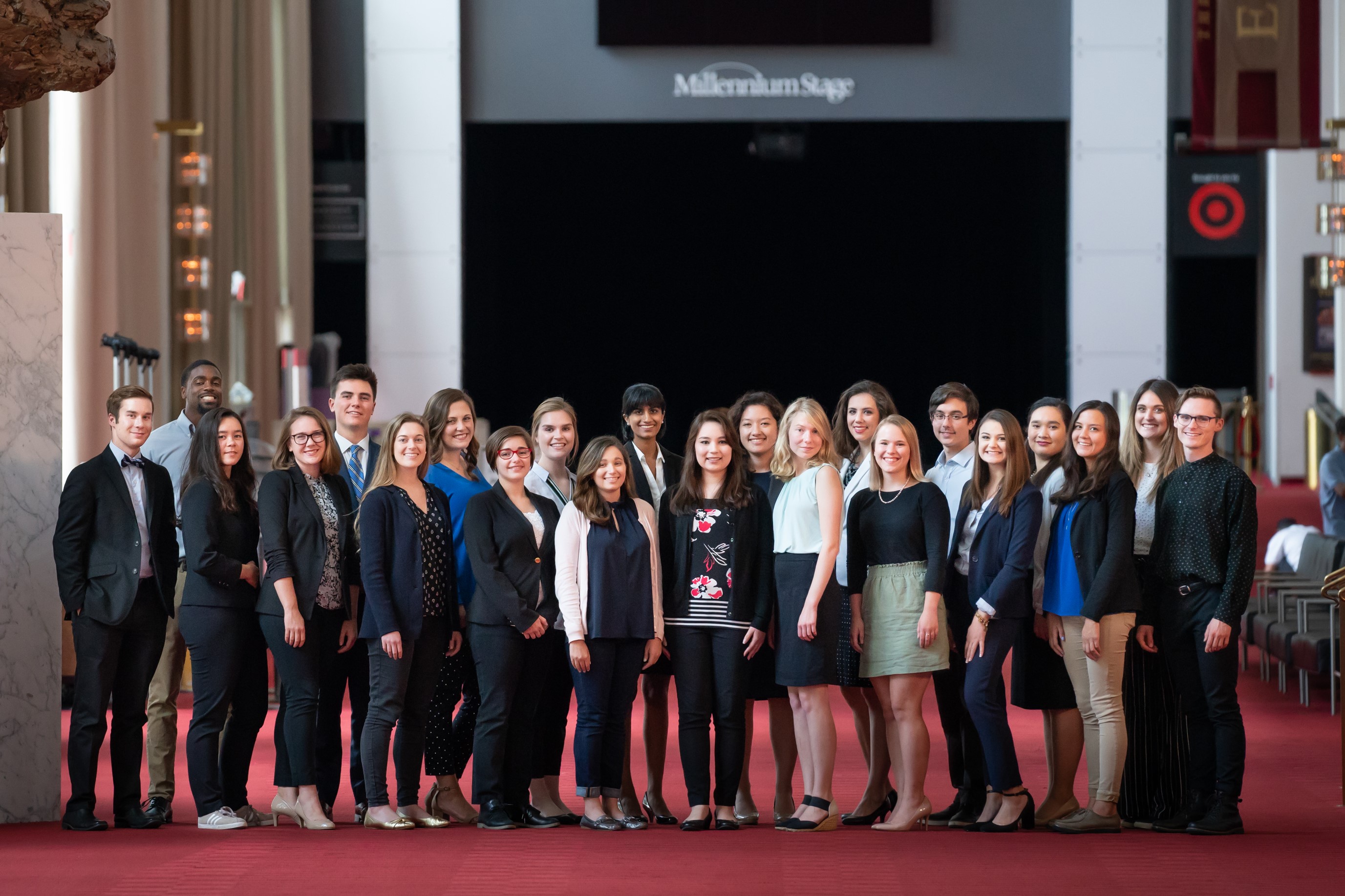 A cohort of interns smiles in the foyer