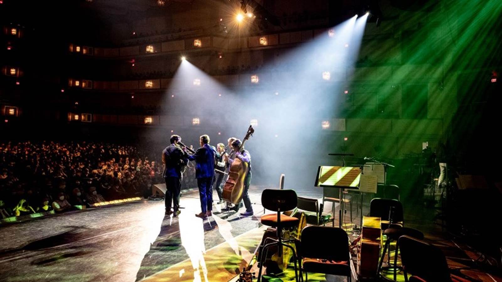 Punch Brothers band shot from behind on stage in the spotlight
