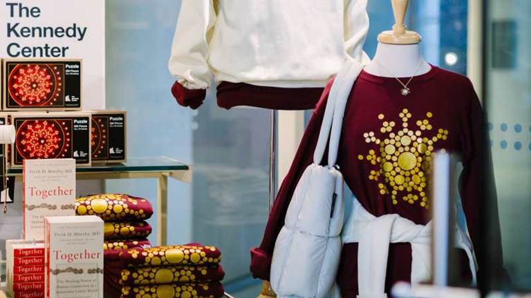 Image of a display in the gift shop showing a sweatshirt with chandelier motif and books.