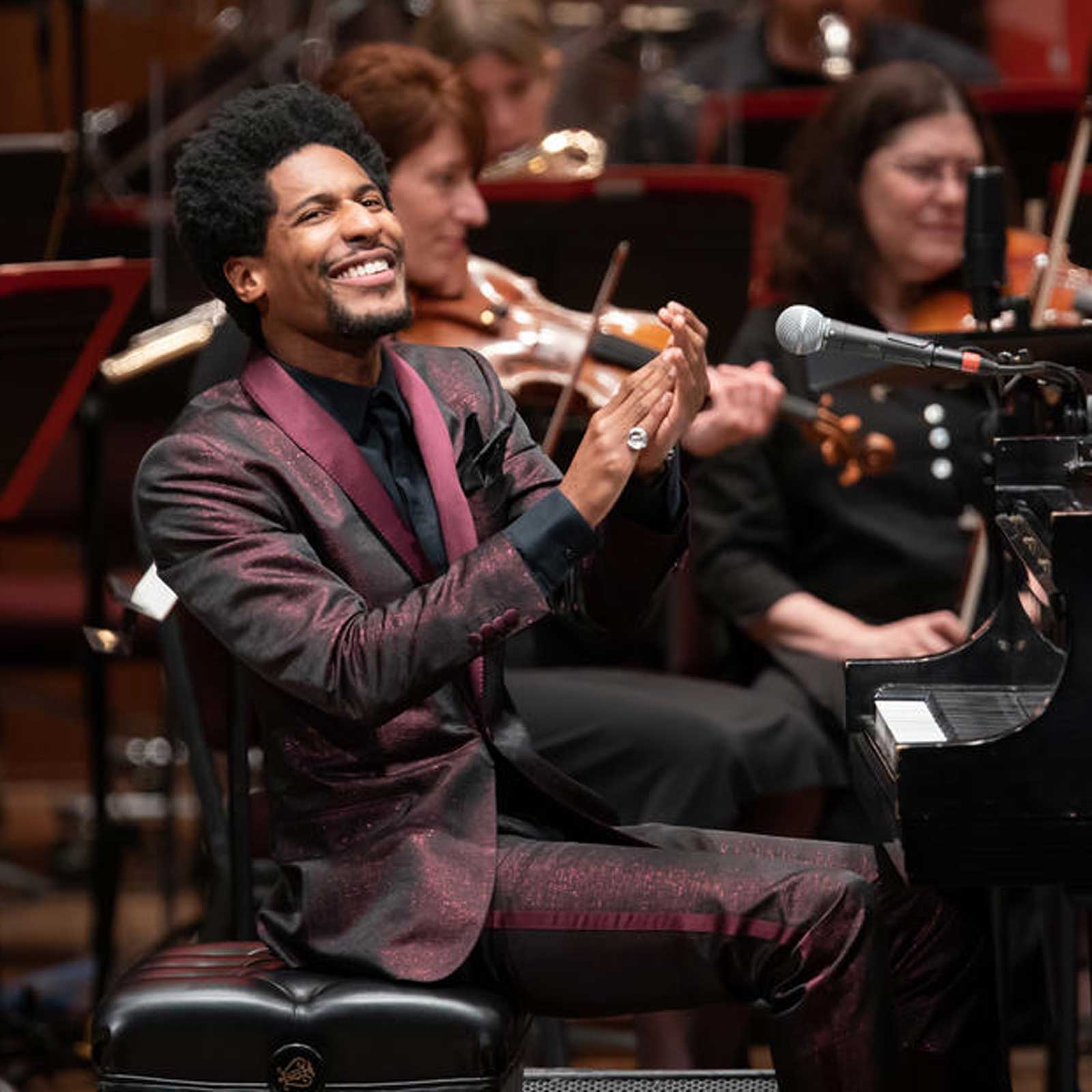 A keyboard player onstage smiling and clapping.