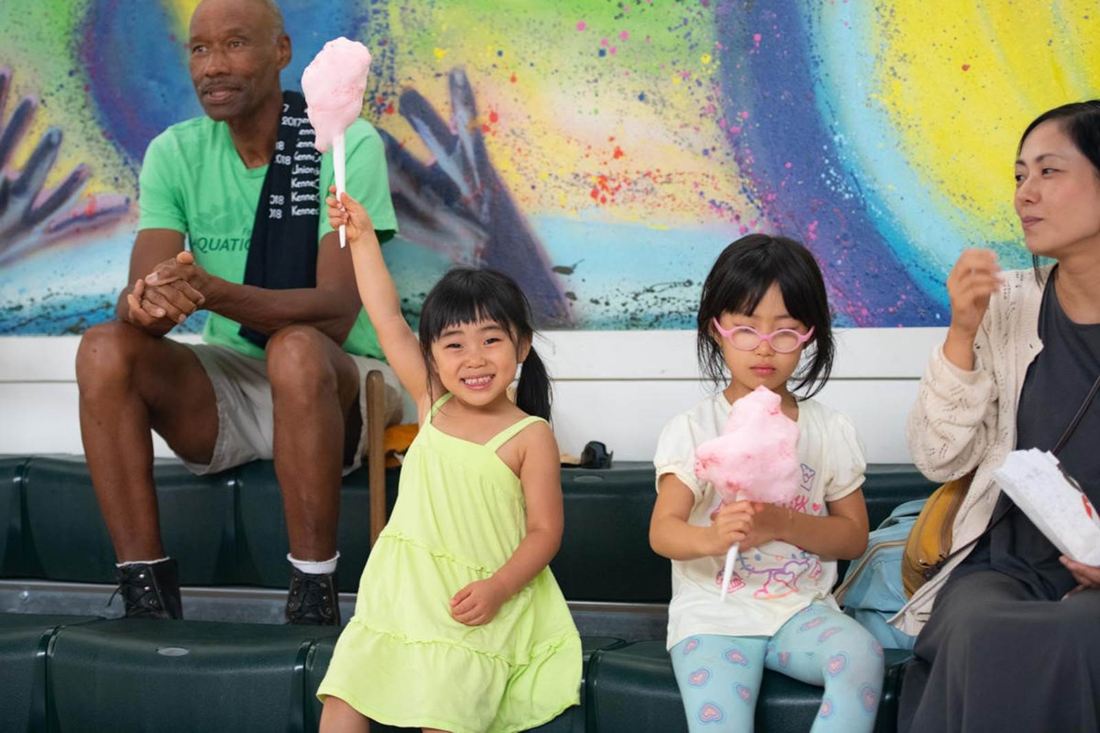 A young girl raising her cotton candy in the air in excitement while watching the National Symphony Orchestra perform in their neighborhood.