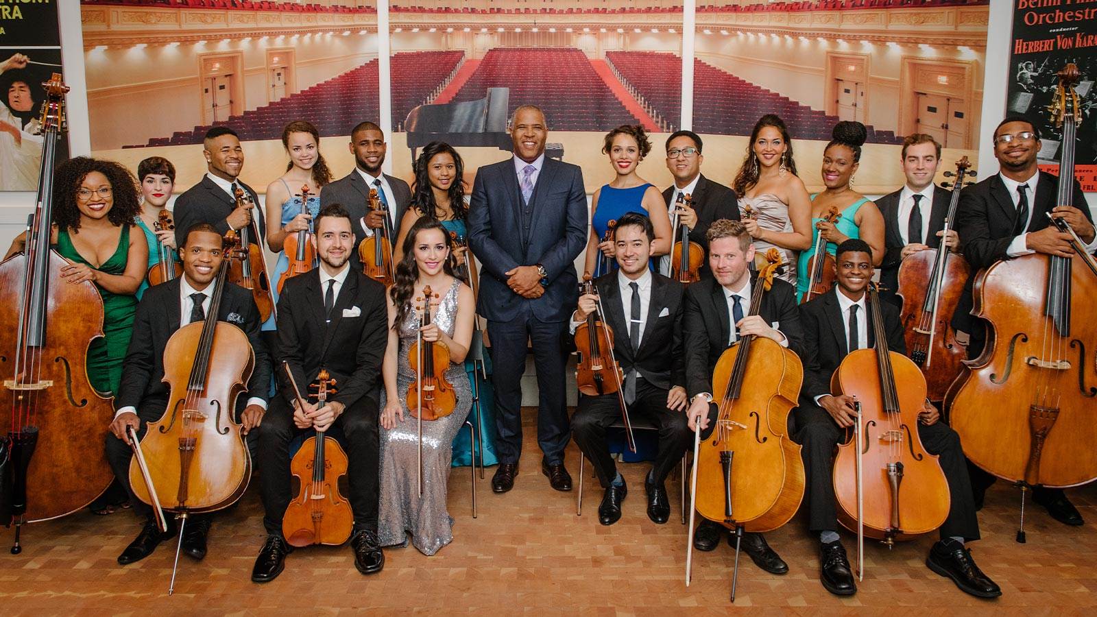 Multiple artists posing with their string instruments in front of show posters.