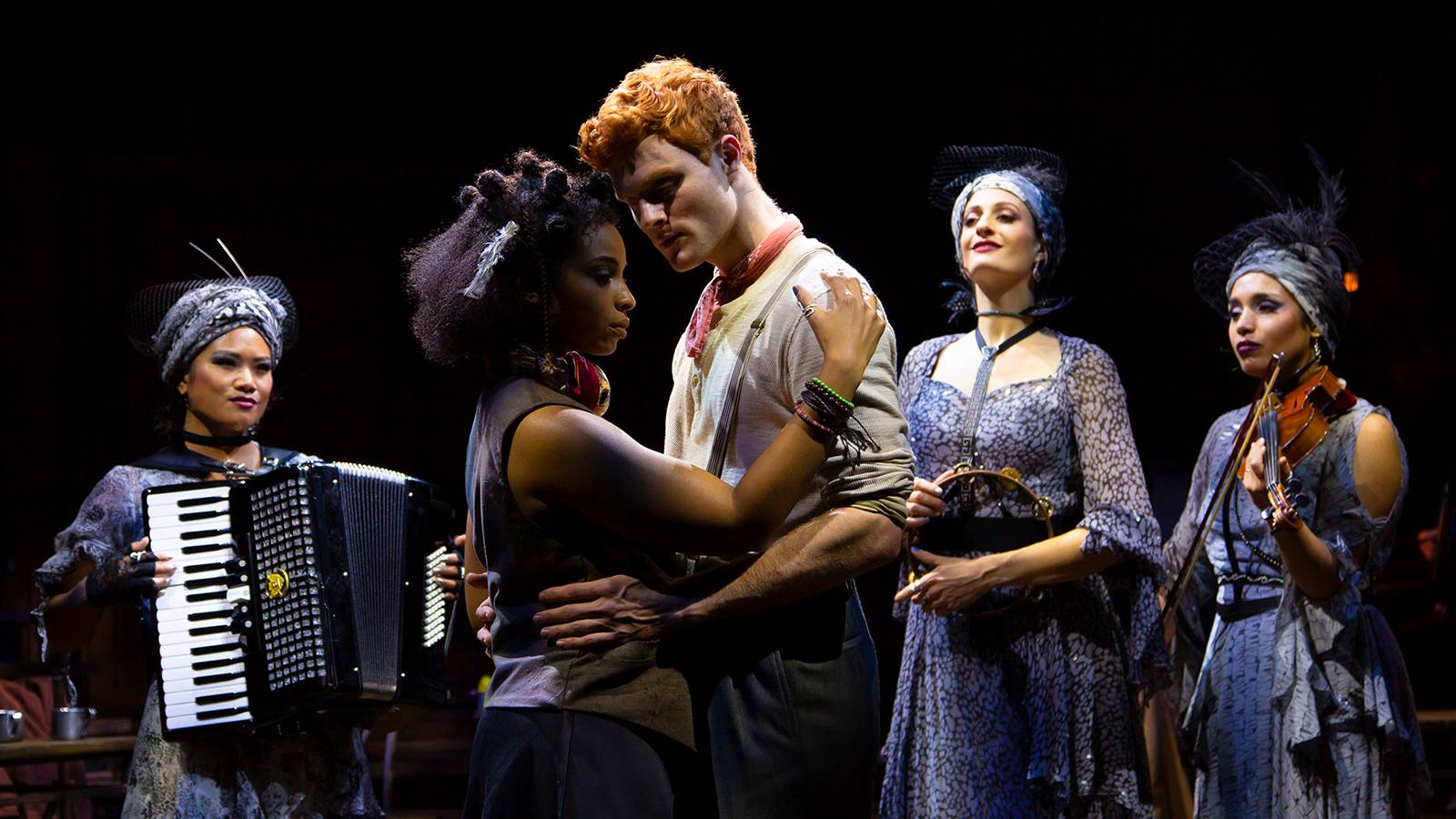 Scene from Hadestown with man and woman embracing surrounded by  3 musicians