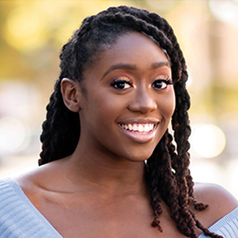 Kanysha Williams with long twisted hair, bright eyes, and greeting smile