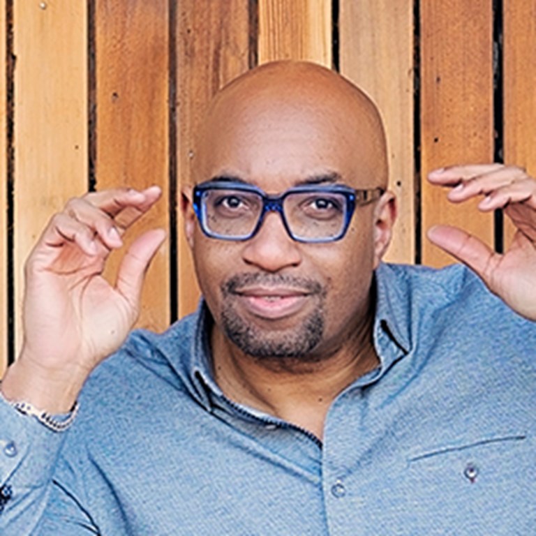 Kwame Alexander pulling his hands away from his blue glasses