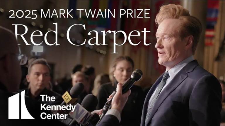 Conan O'Brien speaks into a microphone on the red carpet ahead of the Mark Twain Prize